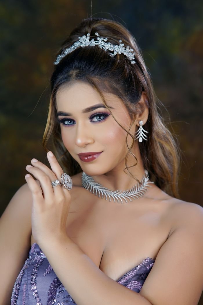 A stunning woman wearing an elegant evening gown and exquisite jewelry, posing gracefully.